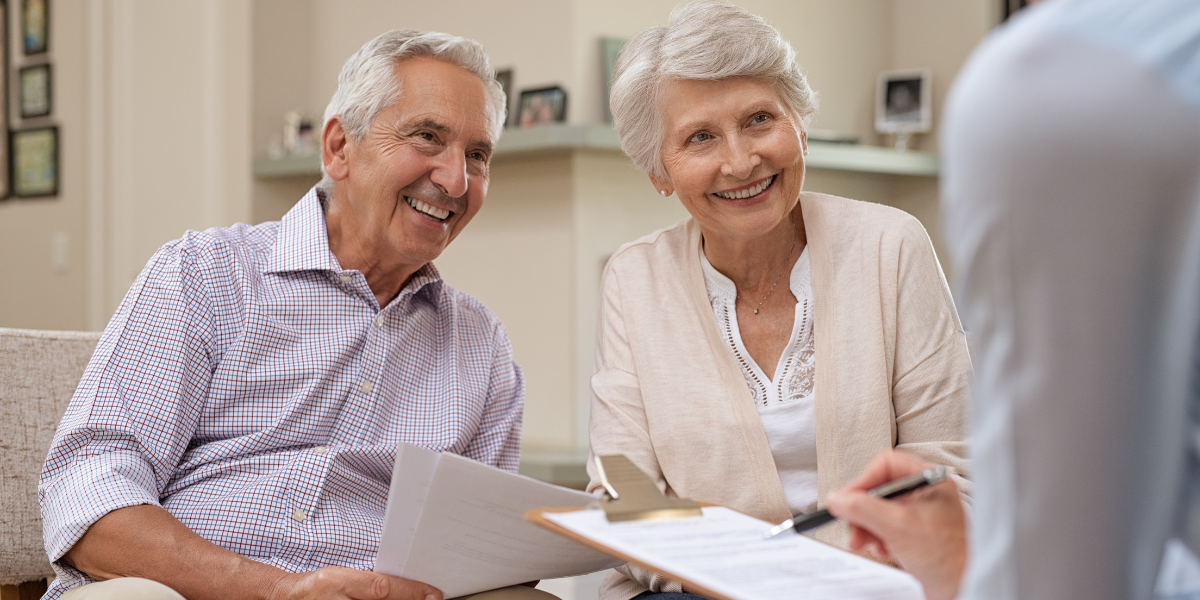 Senior couple meeting with a financial advisor to review Medicare options during Financial Planning Month, emphasizing the importance of healthcare decisions in retirement planning.